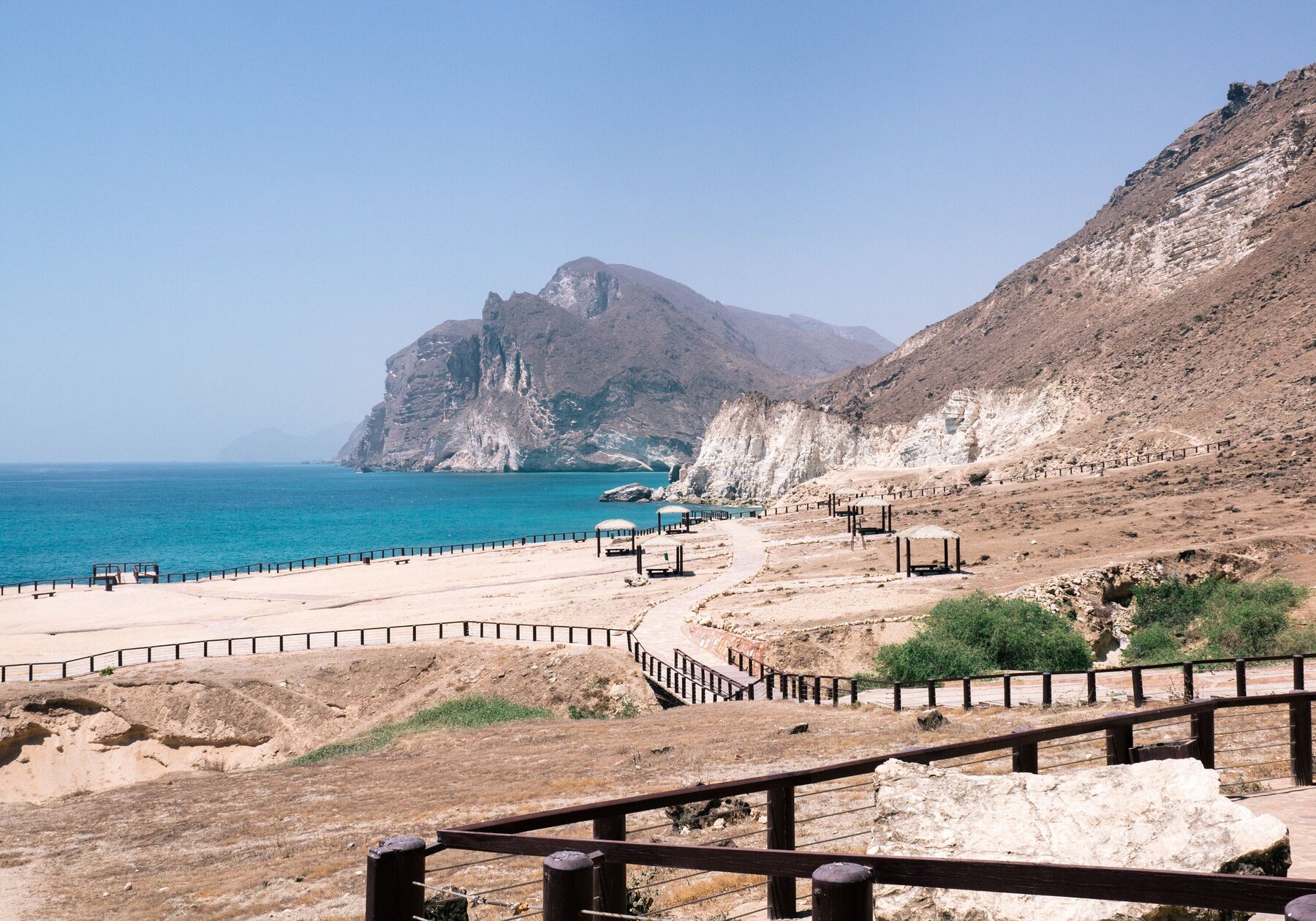The Dhofar coast at Mughsayl near Salalah: turquoise sea beneath white cliffs and a rocky headland under a clear sky
